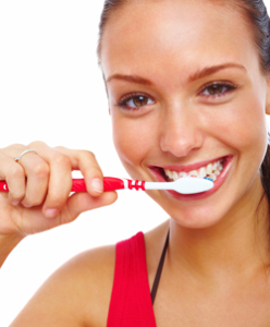 Pretty young woman brushing her teeth isolated